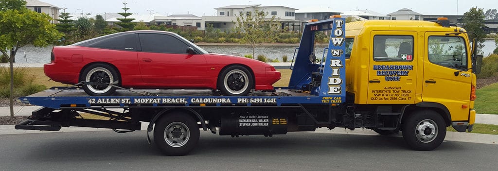 Caloundra towing company tow n ride is towing a red prestige car interstate.